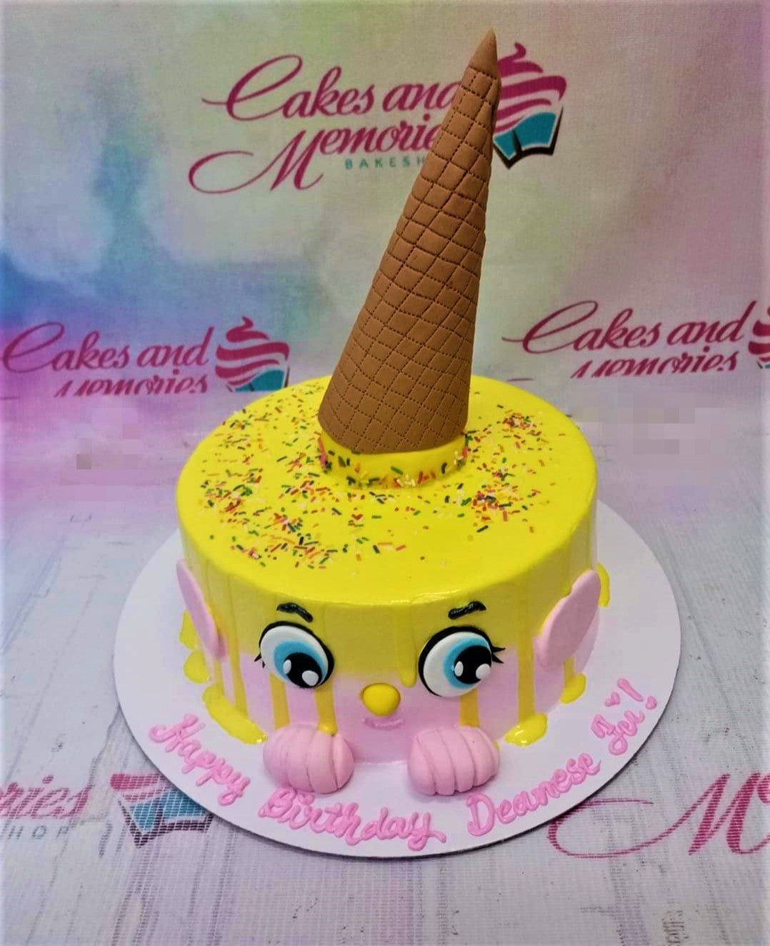 Yellow and pink Shopkins themed cake with a large brown ice cream cone topper and colorful sprinkles. Yellow and pink Shopkins themed cake with a large brown ice cream cone topper and colorful sprinkles.