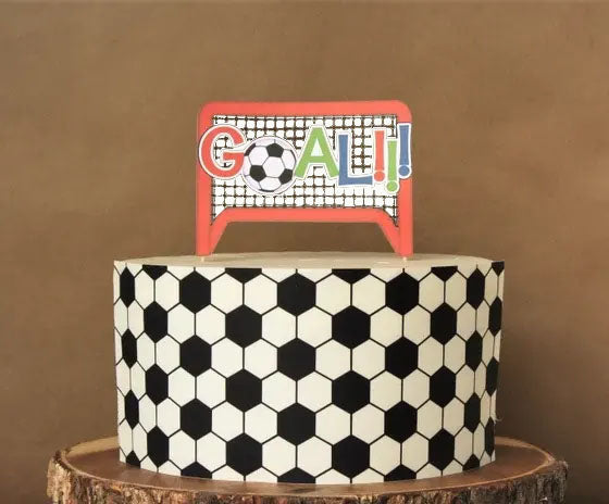 Soccer themed birthday cake with a black and white hexagon pattern and a GOAL topper on a wooden base. Soccer themed birthday cake with a black and white hexagon pattern and a GOAL topper on a wooden base.