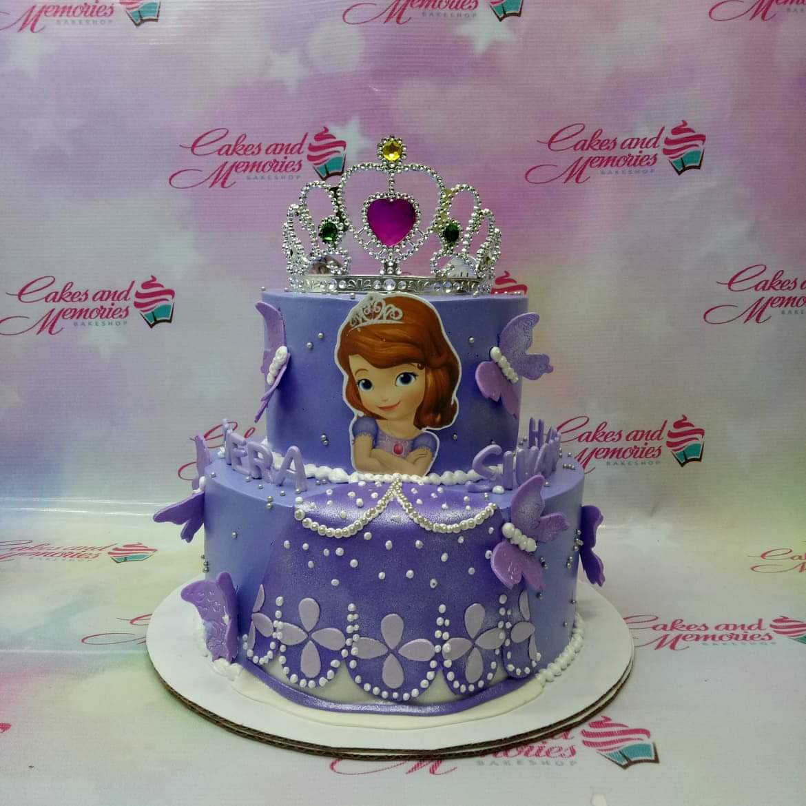 Two-tier purple Sofia the First themed cake with a silver rhinestone tiara, purple butterflies, and white pearl icing details. Two-tier purple Sofia the First themed cake with a silver rhinestone tiara, purple butterflies, and white pearl icing details.