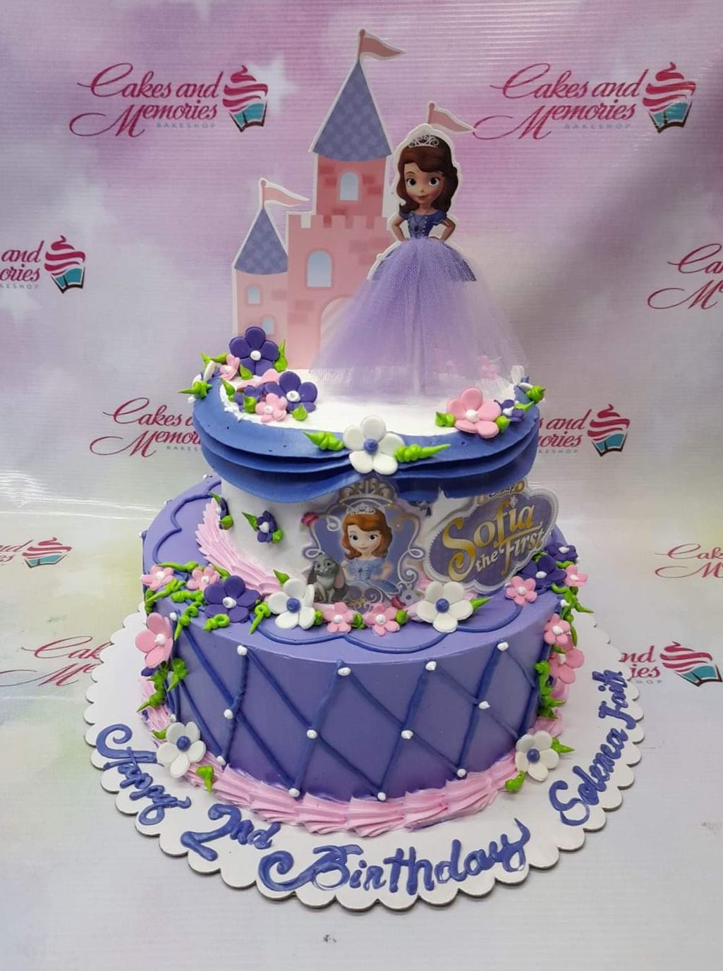 Two-tier Sofia the First themed birthday cake in purple and white with a castle topper and Sofia figurine. Two-tier Sofia the First themed birthday cake in purple and white with a castle topper and Sofia figurine.