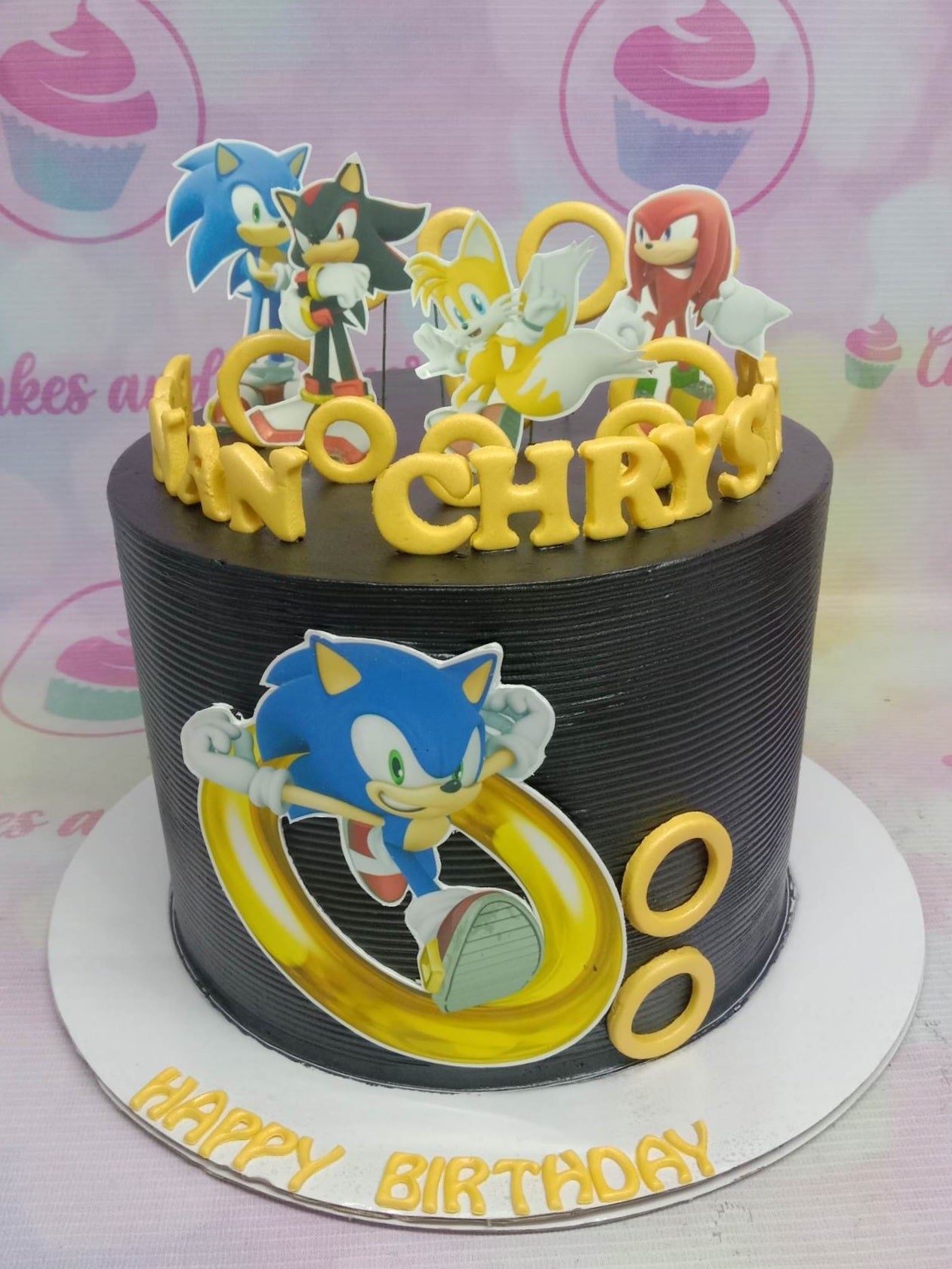 Black textured soft icing cake with Sonic the Hedgehog characters and yellow rings Black textured soft icing cake with Sonic the Hedgehog characters and yellow rings