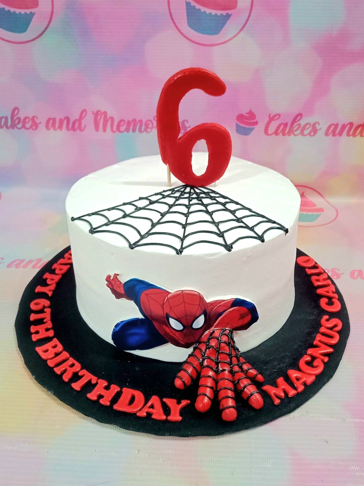 White Spiderman birthday cake with a black piped web design, a Spiderman printout, and a large red number 6 topper. White Spiderman birthday cake with a black piped web design, a Spiderman printout, and a large red number 6 topper.