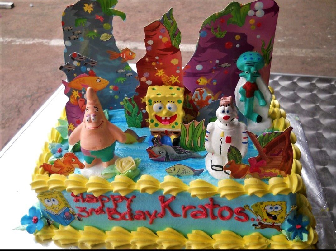 SpongeBob SquarePants themed rectangle cake with 3D figures of SpongeBob, Patrick, Squidward, and Sandy Cheeks on a blue sea-themed icing. SpongeBob SquarePants themed rectangle cake with 3D figures of SpongeBob, Patrick, Squidward, and Sandy Cheeks on a blue sea-themed icing.