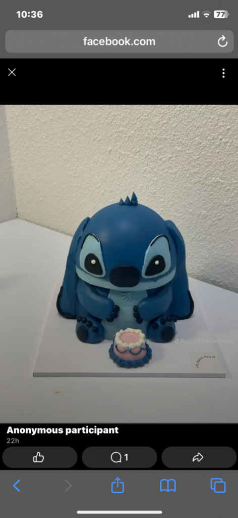 Blue Stitch character shaped cake with a small pink and blue mini cake accessory on a white base board. Blue Stitch character shaped cake with a small pink and blue mini cake accessory on a white base board.