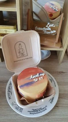 Bento cake with sunset-inspired orange, purple, and yellow palette knife icing and white piped message. Bento cake with sunset-inspired orange, purple, and yellow palette knife icing and white piped message.