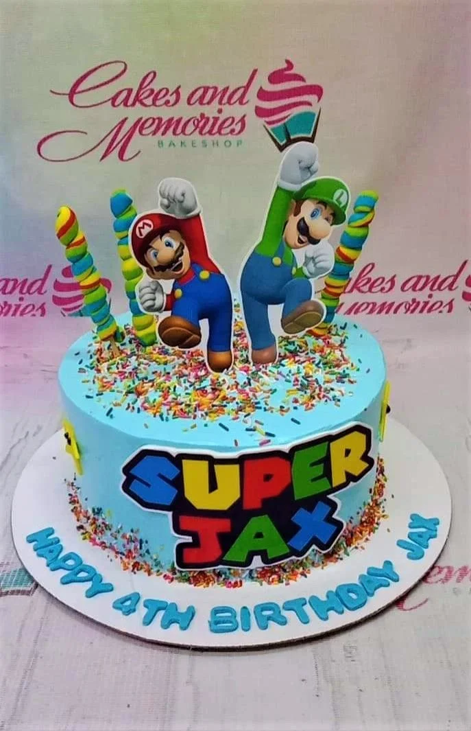 Light blue Super Mario themed birthday cake with Mario and Luigi toppers, colorful sprinkles, and a custom Super Jax logo. Light blue Super Mario themed birthday cake with Mario and Luigi toppers, colorful sprinkles, and a custom Super Jax logo.