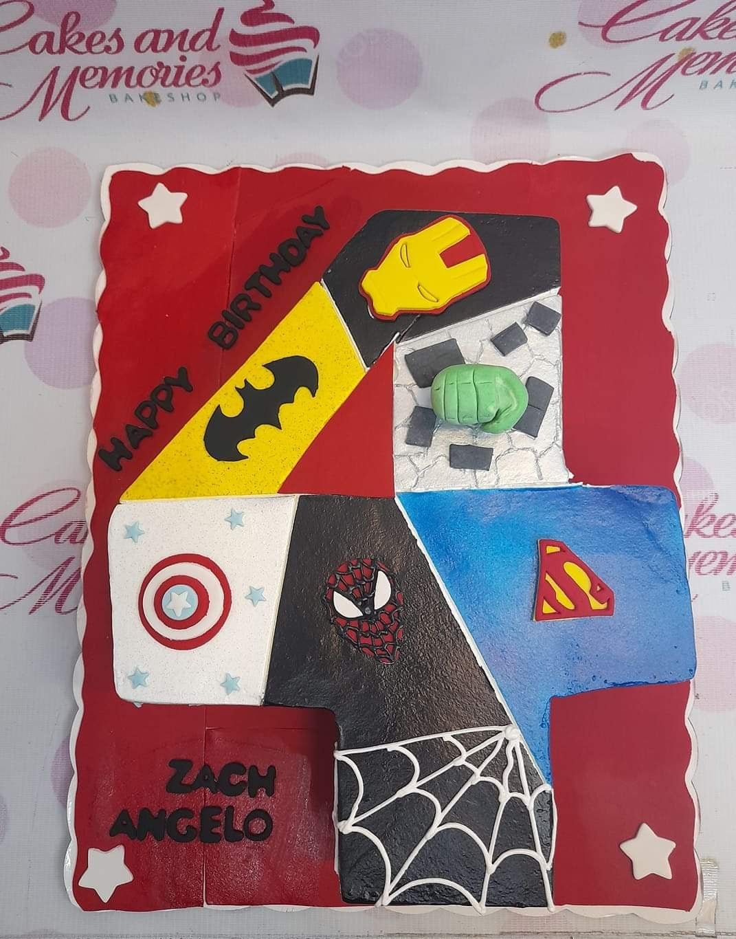 Square red superhero themed birthday cake for Zach Angelo featuring Batman, Iron Man, Hulk, Captain America, Spiderman, and Superman logos. Square red superhero themed birthday cake for Zach Angelo featuring Batman, Iron Man, Hulk, Captain America, Spiderman, and Superman logos.