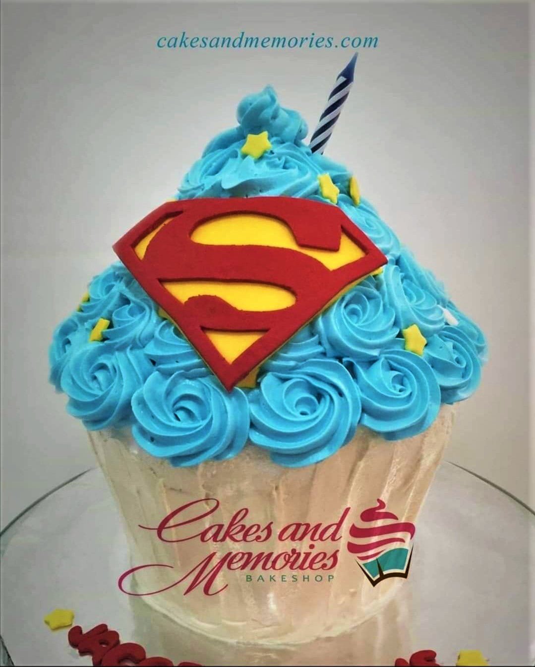 Superman giant cupcake cake with blue icing rosettes and a large red and yellow Superman logo topper. Superman giant cupcake cake with blue icing rosettes and a large red and yellow Superman logo topper.