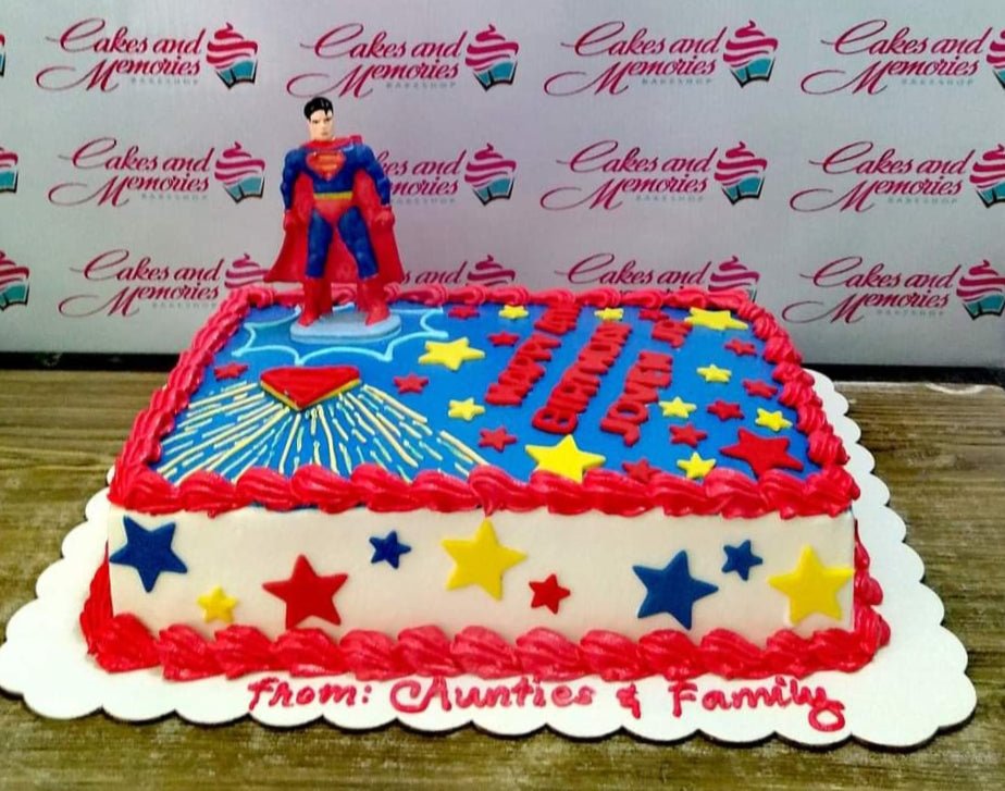 Superman themed rectangle cake with blue icing, red borders, and yellow stars featuring a Superman figurine. Superman themed rectangle cake with blue icing, red borders, and yellow stars featuring a Superman figurine.