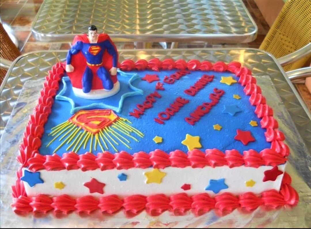 Superman themed rectangle birthday cake with blue icing, red borders, and a Superman figurine topper. Superman themed rectangle birthday cake with blue icing, red borders, and a Superman figurine topper.