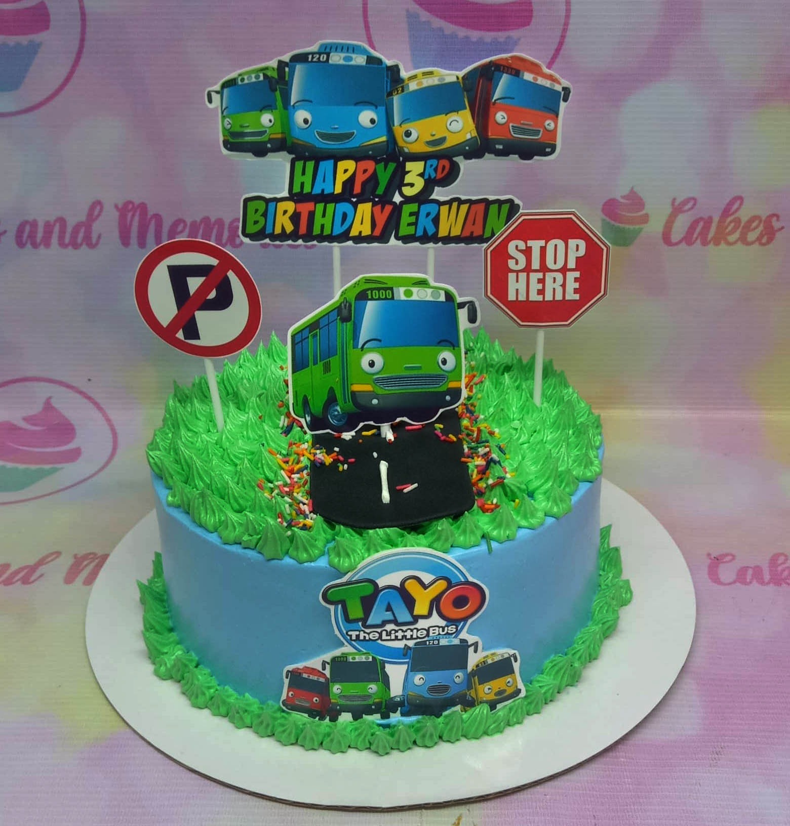 Tayo the Little Bus themed birthday cake with blue icing, green grass piping, and character printouts. Tayo the Little Bus themed birthday cake with blue icing, green grass piping, and character printouts.