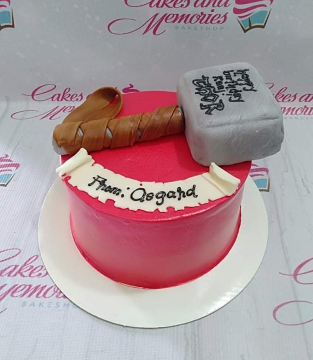 Red Thor hammer birthday cake with a large grey fondant Mjolnir topper and a white scroll message from Asgard. Red Thor hammer birthday cake with a large grey fondant Mjolnir topper and a white scroll message from Asgard.