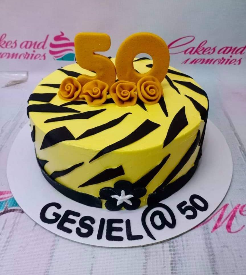 Yellow tiger print birthday cake with gold number 50 and rose toppers on a white base board. Yellow tiger print birthday cake with gold number 50 and rose toppers on a white base board.