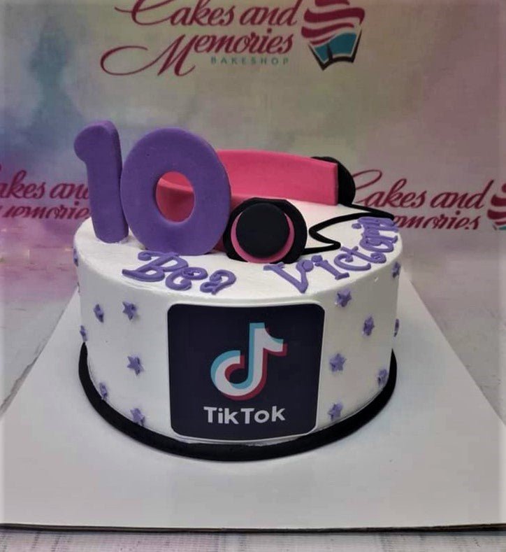 White TikTok themed birthday cake with purple number 10, pink headphones, and purple stars for Bea Victoria. White TikTok themed birthday cake with purple number 10, pink headphones, and purple stars for Bea Victoria.