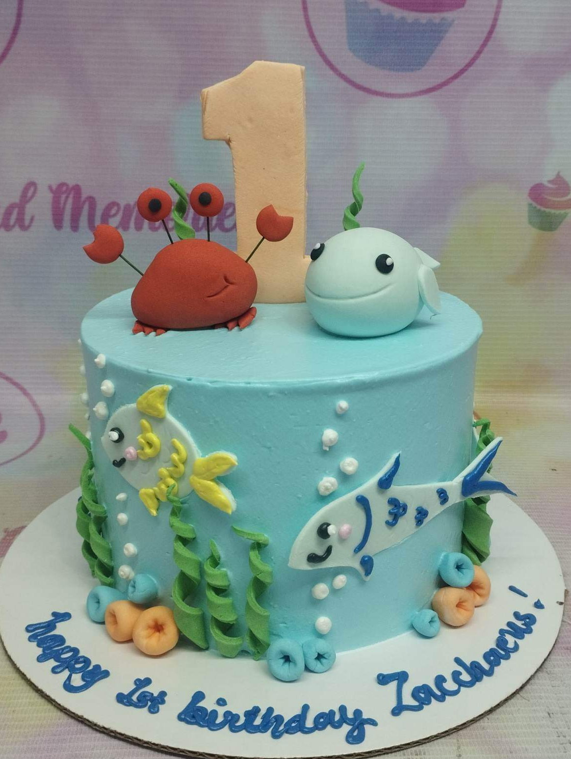 Under the sea themed blue birthday cake with a red crab, blue whale, and colorful fish decorations. Under the sea themed blue birthday cake with a red crab, blue whale, and colorful fish decorations.