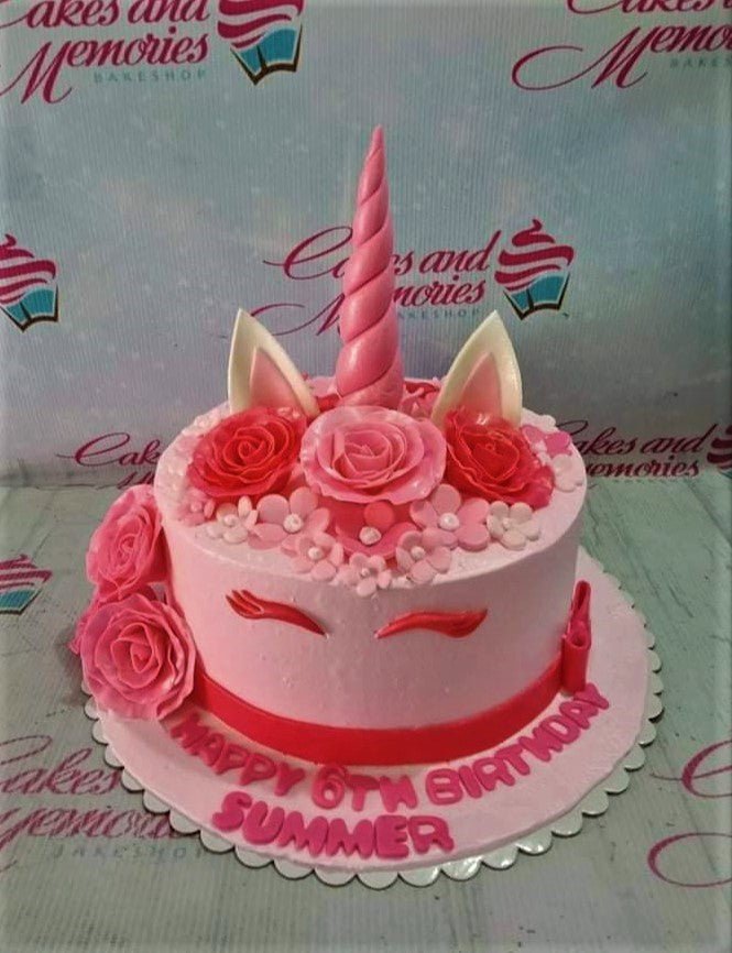 Pink unicorn birthday cake with a pink horn, ears, and fondant roses on a pink base board with a birthday message. Pink unicorn birthday cake with a pink horn, ears, and fondant roses on a pink base board with a birthday message.