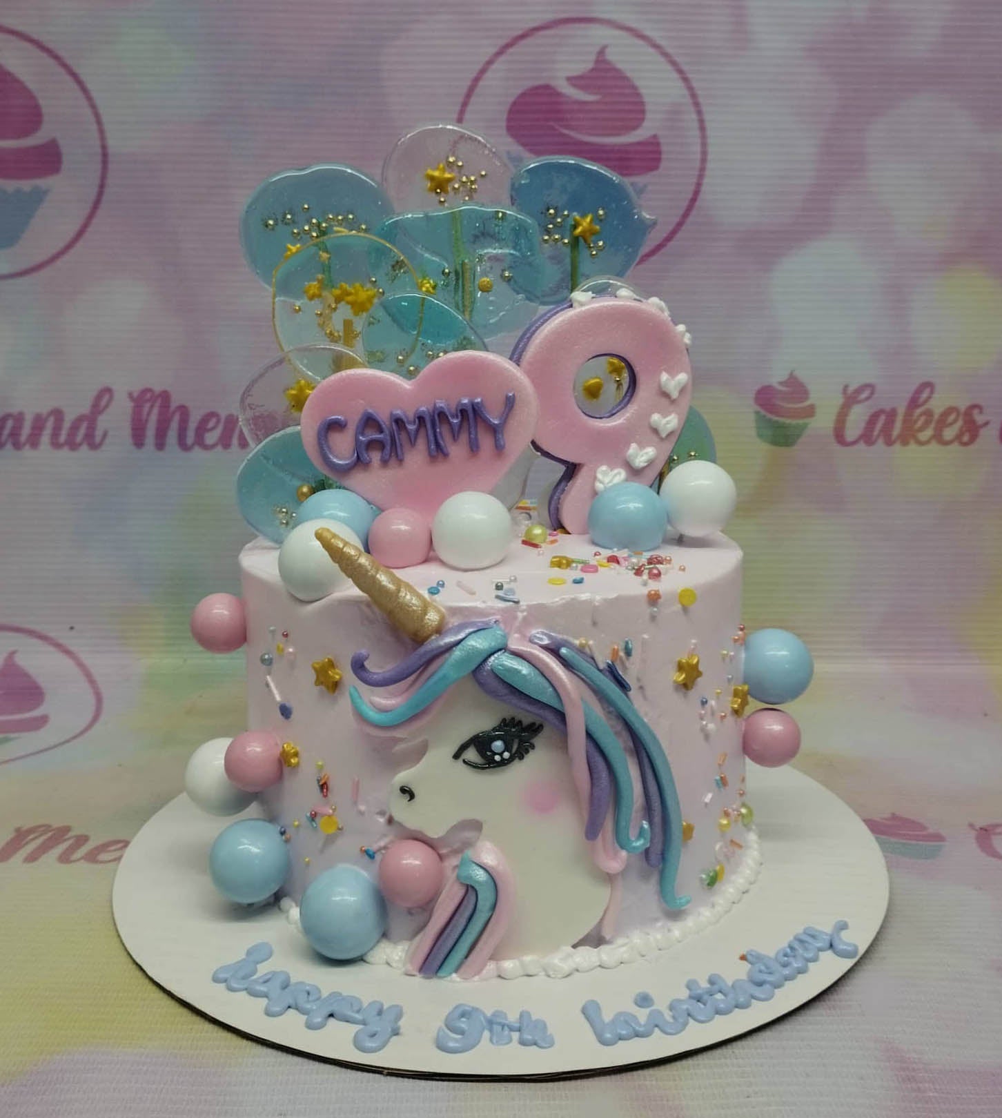 Pink unicorn birthday cake with a large fondant unicorn face, pink heart topper, and blue isomalt lollipops. Pink unicorn birthday cake with a large fondant unicorn face, pink heart topper, and blue isomalt lollipops.