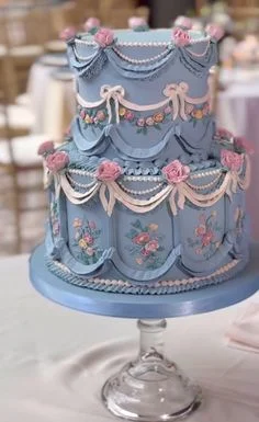 Elegant 2-tier light blue vintage cake with pink fondant roses, white icing swags, and pearl bead details.