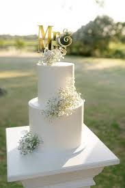 Elegant white two-tier wedding cake decorated with fresh baby's breath flowers and a gold Mr and Mrs topper Elegant white two-tier wedding cake decorated with fresh baby's breath flowers and a gold Mr and Mrs topper