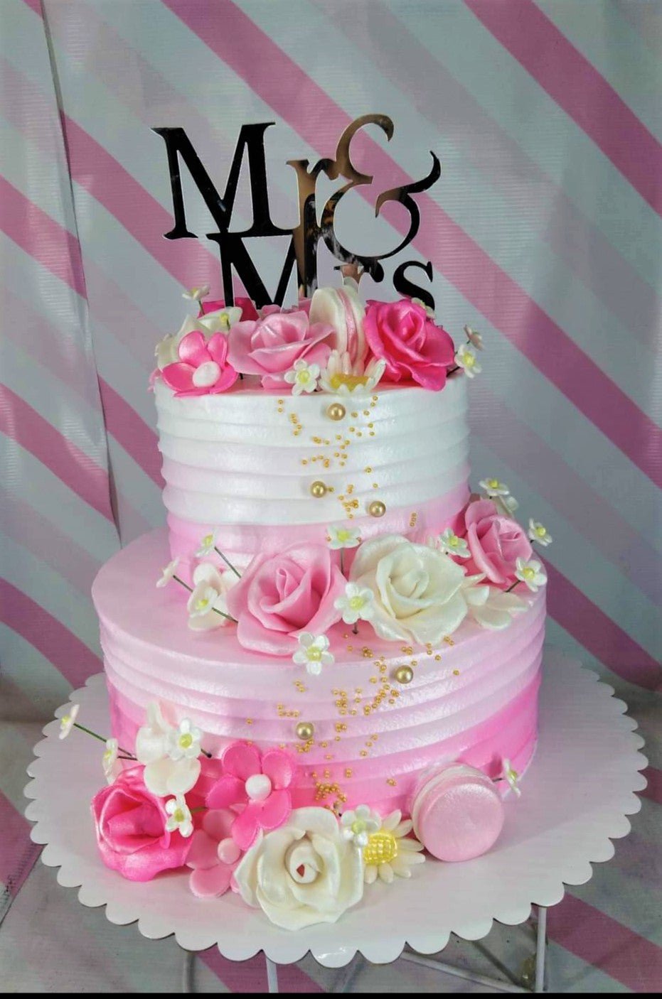 Two-tier pink and white ombre cake with horizontal icing ridges, decorated with pink and white gumpaste roses and a gold Mr & Mrs topper. Two-tier pink and white ombre cake with horizontal icing ridges, decorated with pink and white gumpaste roses and a gold Mr & Mrs topper.