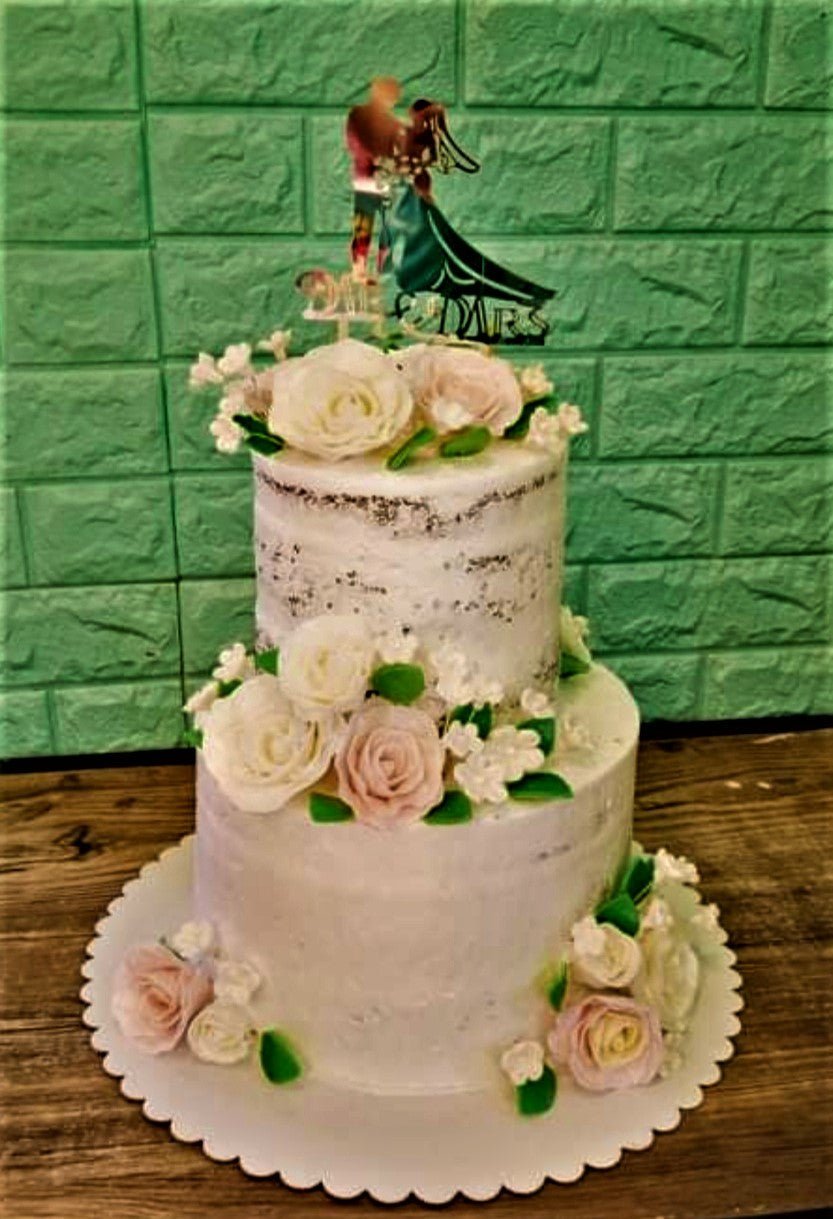 Two-tier semi-naked wedding cake decorated with white and pink edible roses and a gold Mr & Mrs topper. Two-tier semi-naked wedding cake decorated with white and pink edible roses and a gold Mr & Mrs topper.