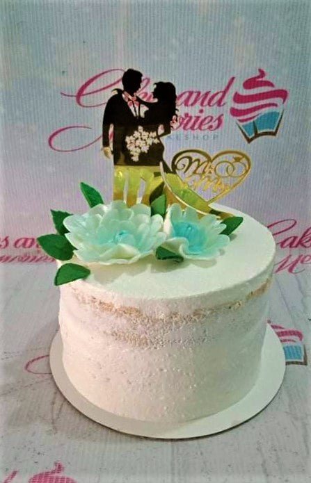 Semi-naked white wedding cake with a black silhouette couple topper, gold Mr & Mrs heart, and light blue gumpaste flowers.