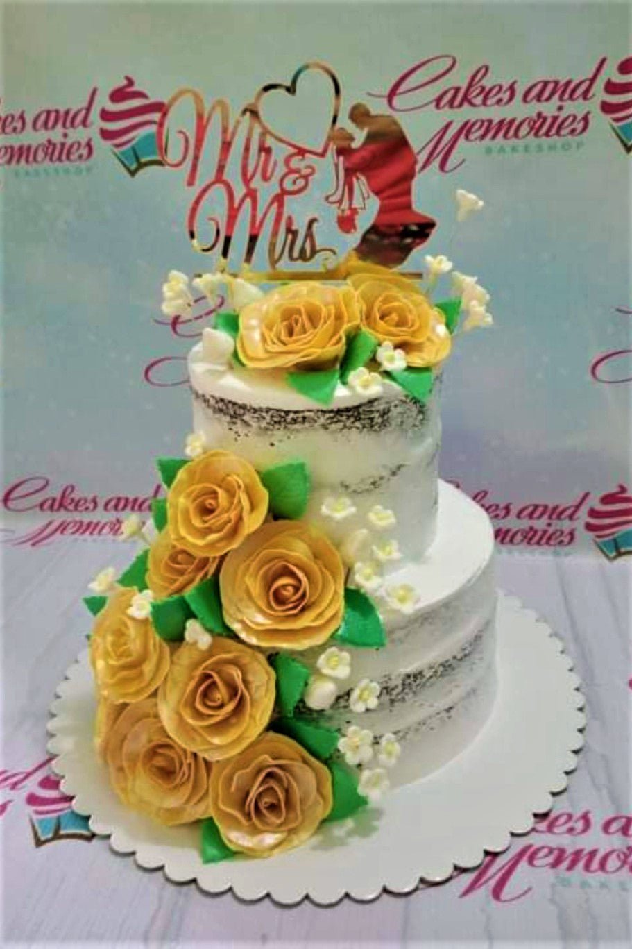 Two-tier semi-naked wedding cake with yellow gumpaste roses and a gold Mr & Mrs topper. Two-tier semi-naked wedding cake with yellow gumpaste roses and a gold Mr & Mrs topper.
