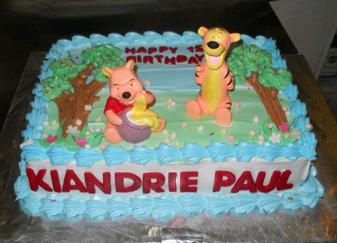 Winnie the Pooh and Tigger themed rectangle birthday cake with blue and green icing, trees, and 3D fondant characters. Winnie the Pooh and Tigger themed rectangle birthday cake with blue and green icing, trees, and 3D fondant characters.