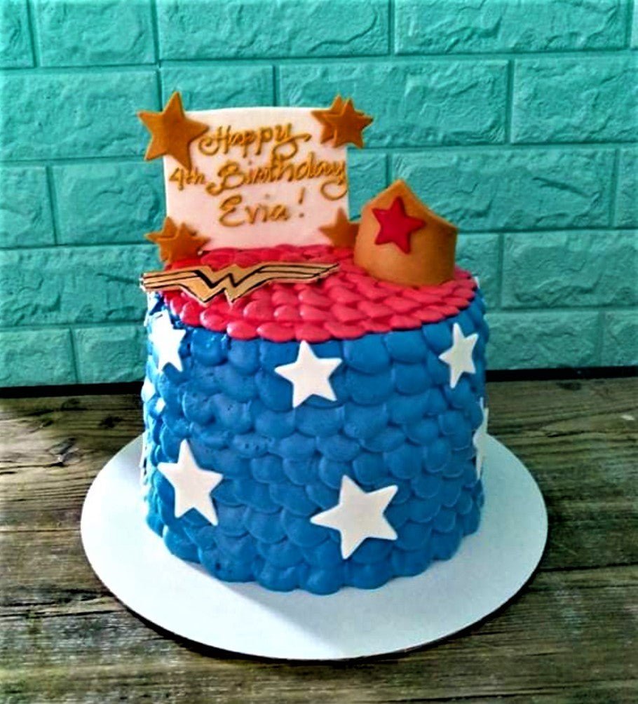Wonder Woman themed birthday cake with blue and red petal icing, white stars, and a gold tiara topper. Wonder Woman themed birthday cake with blue and red petal icing, white stars, and a gold tiara topper.