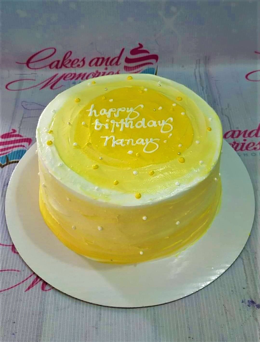 Yellow and white minimalist birthday cake with a textured icing finish and white pearl sprinkles.