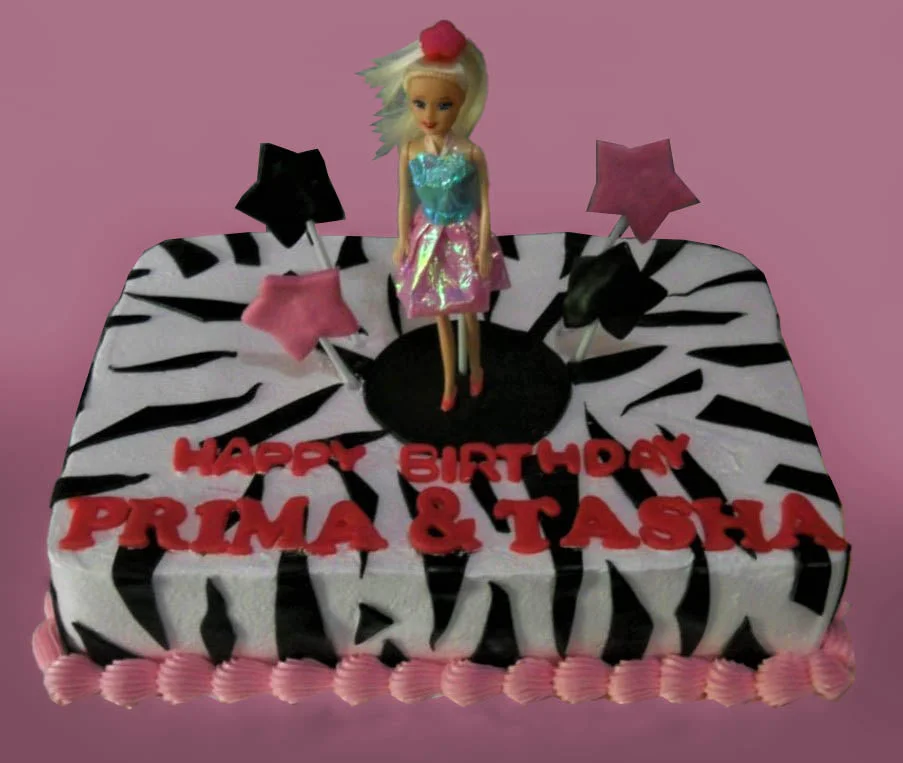 Zebra Doll Rectangle Birthday Cake Rectangle birthday cake with black and white zebra print icing, pink shell borders, and a doll topper with star accents.