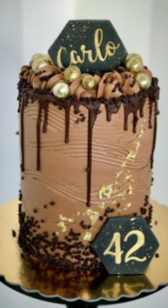 Tall chocolate brown cake with dark chocolate drip, gold leaf accents, and black hexagonal toppers for a 42nd birthday. Tall chocolate brown cake with dark chocolate drip, gold leaf accents, and black hexagonal toppers for a 42nd birthday.