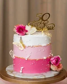 Elegant 50 and Fabulous birthday cake with pink and white ombre icing, gold butterflies, and fresh roses.