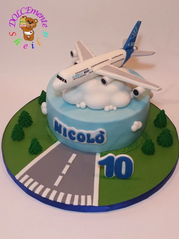 Light blue fondant airplane cake with a large 3D Airbus A380 topper, white clouds, and a fondant runway on a green baseboard. Light blue fondant airplane cake with a large 3D Airbus A380 topper, white clouds, and a fondant runway on a green baseboard.