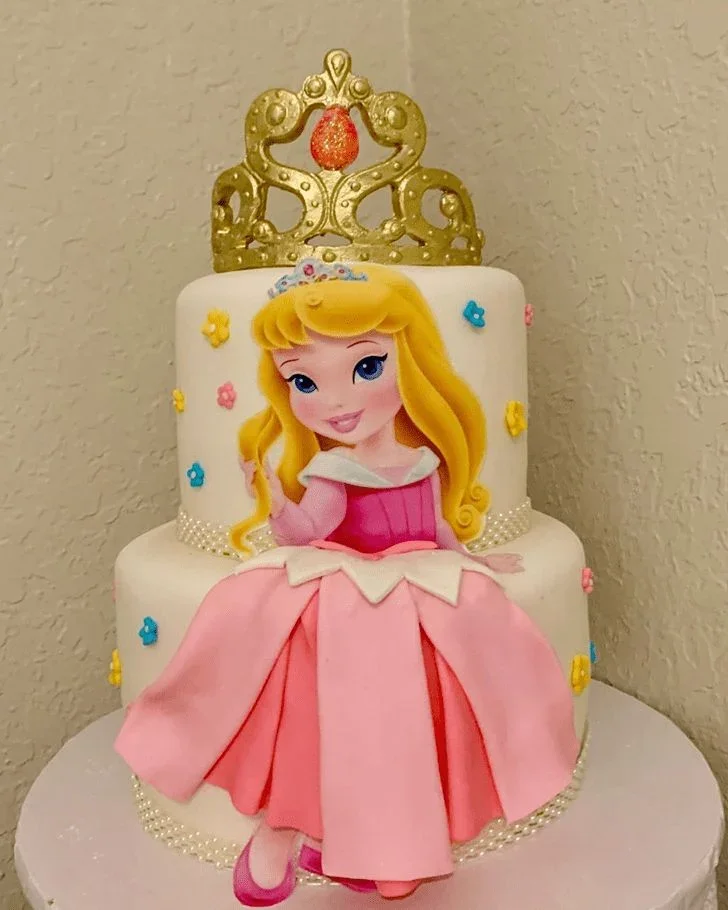 White 2-tier fondant cake with a gold crown topper and a large Aurora princess printout on the front