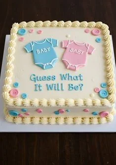 Baby Gender Reveal Ivory Cake Ivory square cake with soft icing, baby gender reveal theme, pink and blue baby onesies, and piped shell borders