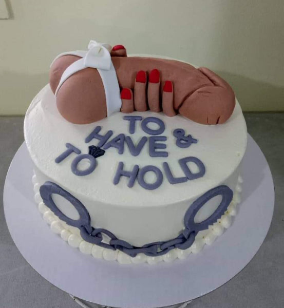 White round cake with a large 3D fondant male anatomy topper and purple gumpaste handcuffs on the side. White round cake with a large 3D fondant male anatomy topper and purple gumpaste handcuffs on the side.