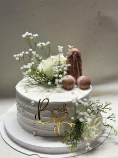 White textured icing cake with fresh white roses, baby's breath, and a humorous brown phallic-shaped fondant topper for a bachelorette party.