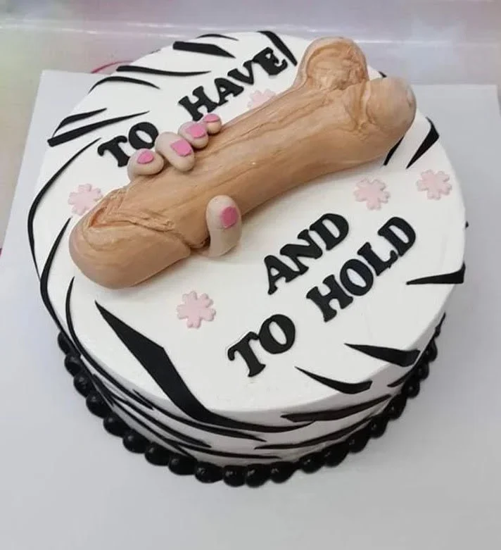 White round cake with black zebra stripes featuring a large tan gumpaste phallic topper being held by a hand with pink nails. White round cake with black zebra stripes featuring a large tan gumpaste phallic topper being held by a hand with pink nails.
