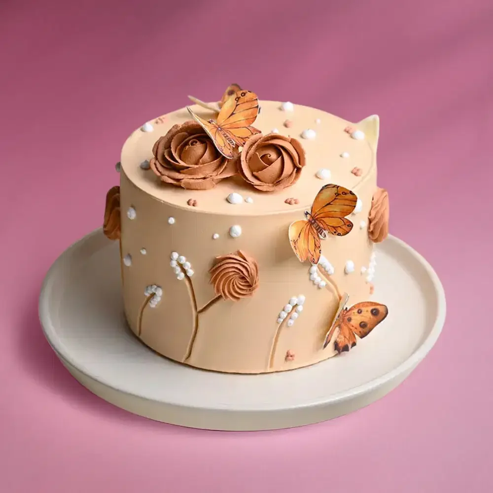 Butterfly Beige Ivory Floral Birthday Cake Beige 1-tier cake with brown piped roses and orange butterfly printouts