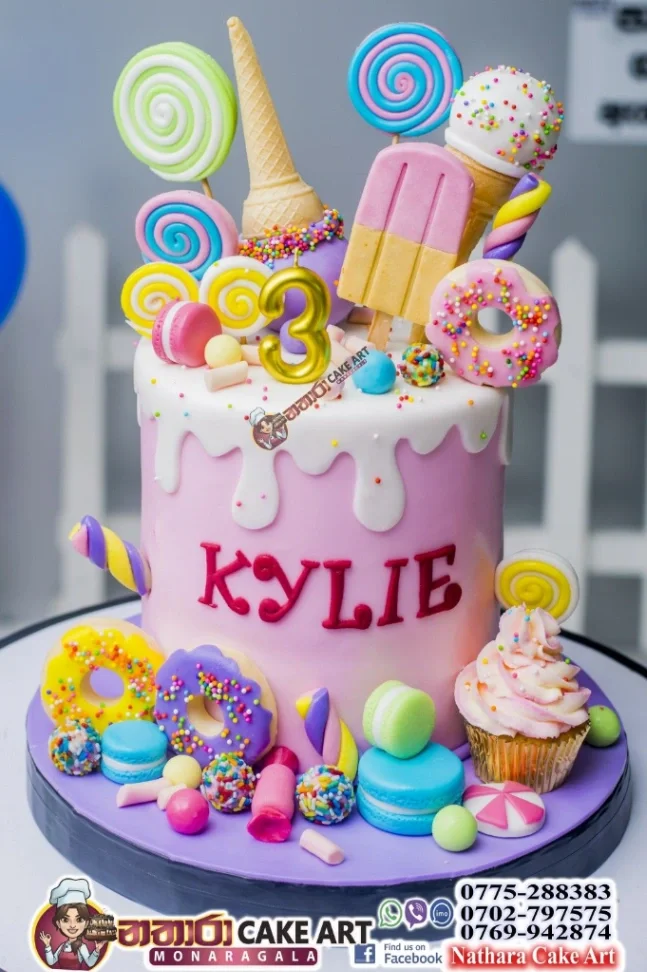 Pink 1-tier candy themed birthday cake with white drip, colorful donuts, ice cream cones, lollipops, and macarons. Pink 1-tier candy themed birthday cake with white drip, colorful donuts, ice cream cones, lollipops, and macarons.