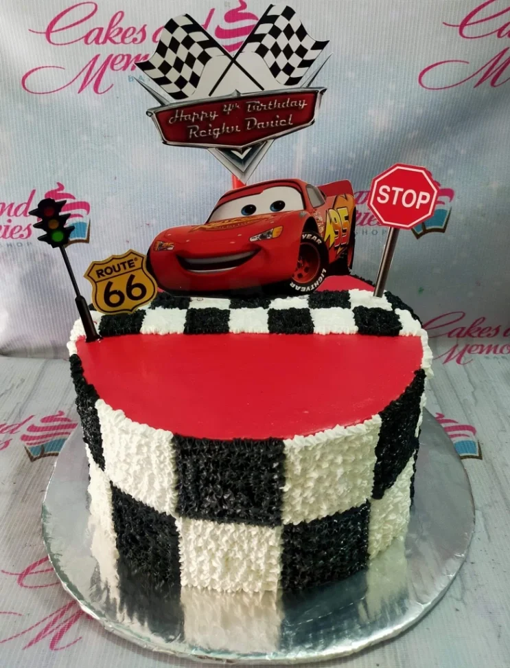 Red and white checkered Cars themed birthday cake with Lightning McQueen printout and racing flags.