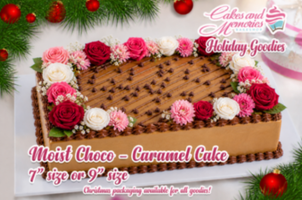 A caramel rectangle cake themed Choco Caramel, featuring chocolate chips, pink, red, and white edible roses, and piped chocolate icing borders.