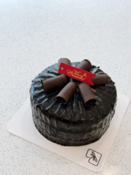 Round chocolate cake with dark chocolate icing, chocolate curls on top, and a red Merry Christmas banner. Round chocolate cake with dark chocolate icing, chocolate curls on top, and a red Merry Christmas banner.