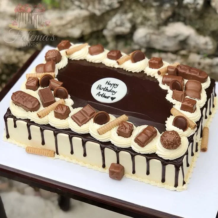 Rectangular chocolate drip cake with white icing, assorted chocolate bars, wafer sticks, and a Happy Birthday Arthur message. Rectangular chocolate drip cake with white icing, assorted chocolate bars, wafer sticks, and a Happy Birthday Arthur message.