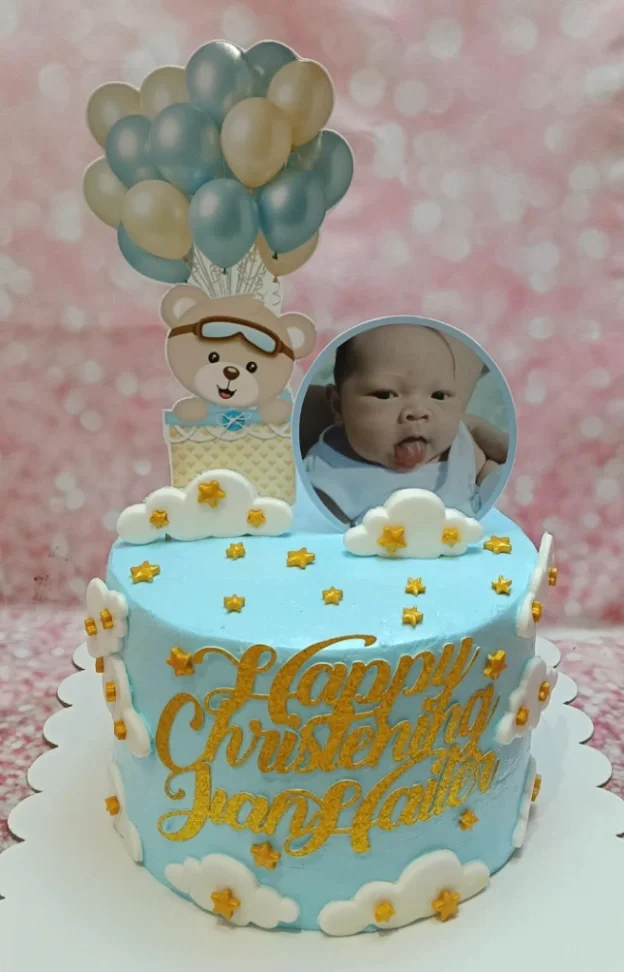 Light blue christening cake for Ivan Hailer featuring a bear in a hot air balloon, a baby photo, and gold glitter message. Light blue christening cake for Ivan Hailer featuring a bear in a hot air balloon, a baby photo, and gold glitter message.