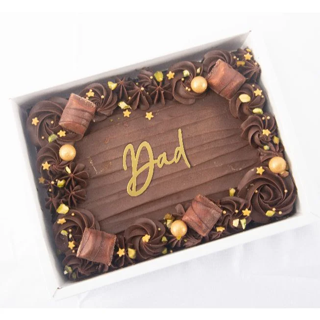 Rectangular chocolate cake for Dad with chocolate swirls, gold stars, and chocolate bar pieces in a white box. Rectangular chocolate cake for Dad with chocolate swirls, gold stars, and chocolate bar pieces in a white box.