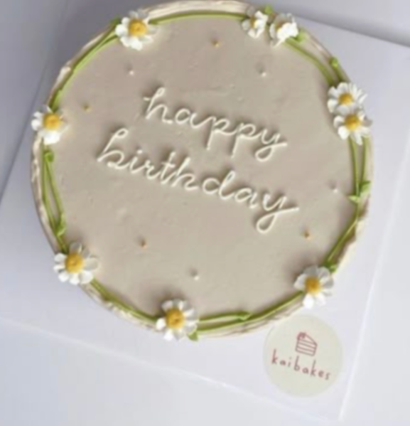 White minimalist birthday cake with piped icing daisies and green stems featuring a Happy Birthday message in white script. White minimalist birthday cake with piped icing daisies and green stems featuring a Happy Birthday message in white script.