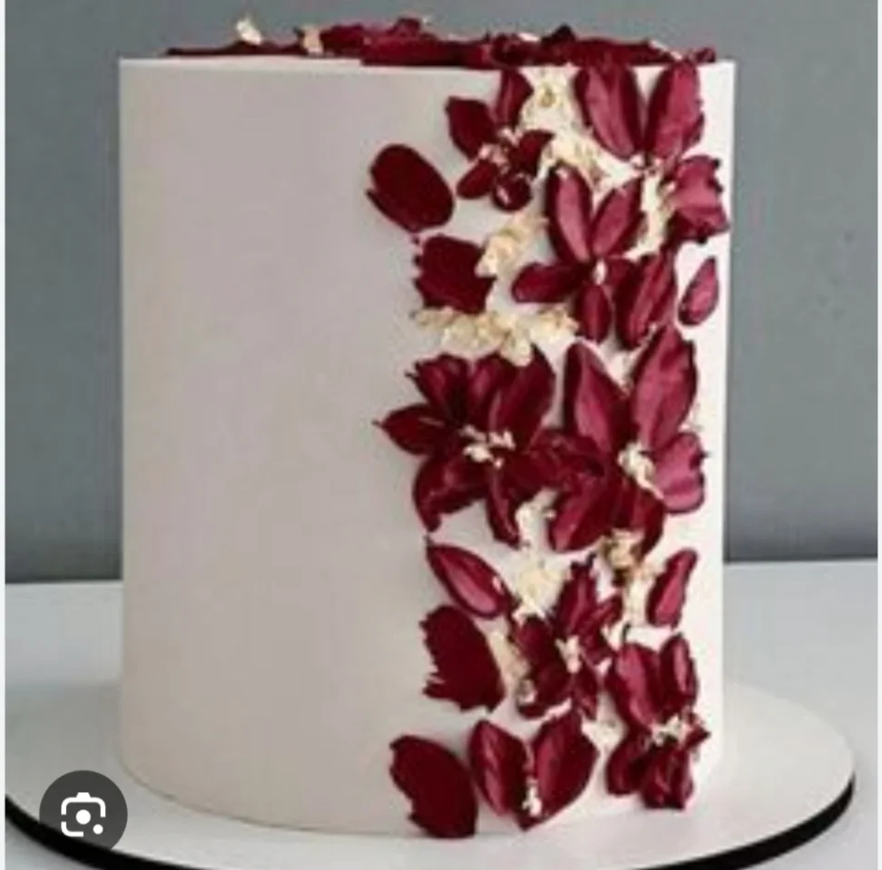 Elegant white single tier cake featuring vertical dark red palette knife icing flowers and gold leaf accents. Elegant white single tier cake featuring vertical dark red palette knife icing flowers and gold leaf accents.
