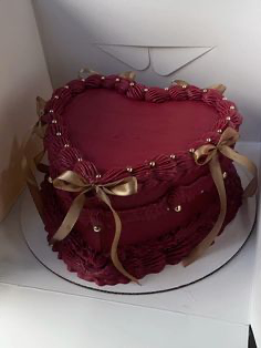 Heart-shaped dark red vintage cake with piped ruffles, gold satin bows, and silver dragees.